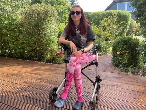 Mit 38 Jahren Rentnerin - drei Jahre nach einer Virus-Infektion Junge Frau sitzt auf einem Rollator auf einer Terrasse
