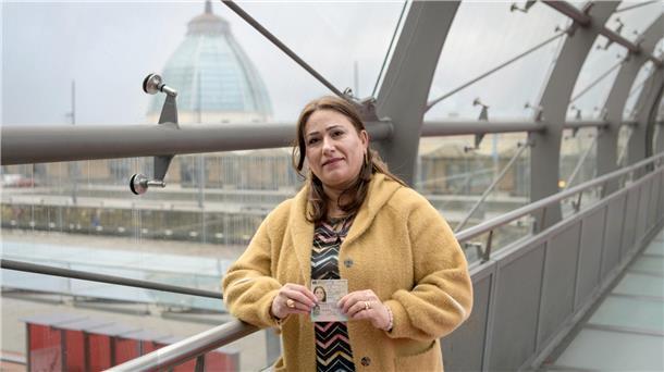 Frau mit einem Ausweis auf einer Brücke