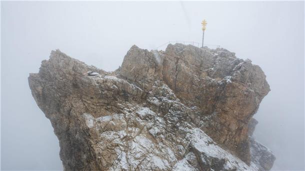 Nebelwolken umhüllen bei Schneetreiben auf der Zugspitze die Aussichtsplattform mit dem Gipfelkreuz (Archivbild). Aus mehreren Bergsteigergruppen wurden Notrufe abgesetzt, nachdem sie aufgrund von Witterung und Neuschnee auf etwa 2500 Metern Höhe nicht mehr weiterkamen.