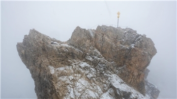 Nebelwolken umhüllen bei Schneetreiben auf der Zugspitze die Aussichtsplattform mit dem Gipfelkreuz (Archivbild). Aus mehreren Bergsteigergruppen wurden Notrufe abgesetzt, nachdem sie aufgrund von Witterung und Neuschnee auf etwa 2500 Metern Höhe nicht mehr weiterkamen.