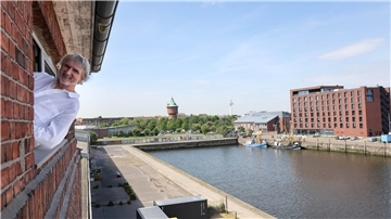 Norbert Plambeck lehnt aus einem Fenster mit Blick auf den Alten Fischereihafen.