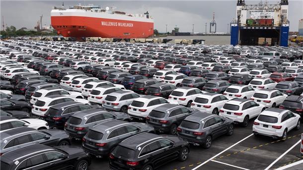Autos parken im Hafen vor Schiffen.