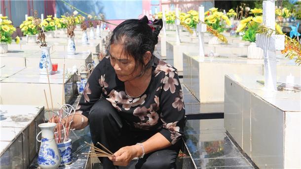 Nguyen Thi Nhiem zündet Räucherstäbchen auf einem Friedhof an und betet für die Seelen der ungeborenen Kinder.