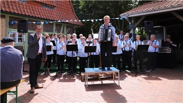 Nieder Ochtenhausens Bürgermeister Stefan Imbusch (links) gratulierte der Singgruppe des Heimatvereins Nieder Ochtenhausen zu ihrem 40-jährigen Bestehen, das am Sonntag mit einem „Bunten Musikfest“ am historischen Kornspeicher gefeiert wurde.