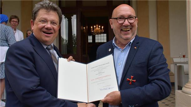 Zwei Männer mit der Urkunde für das Bundesverdienstkreuz