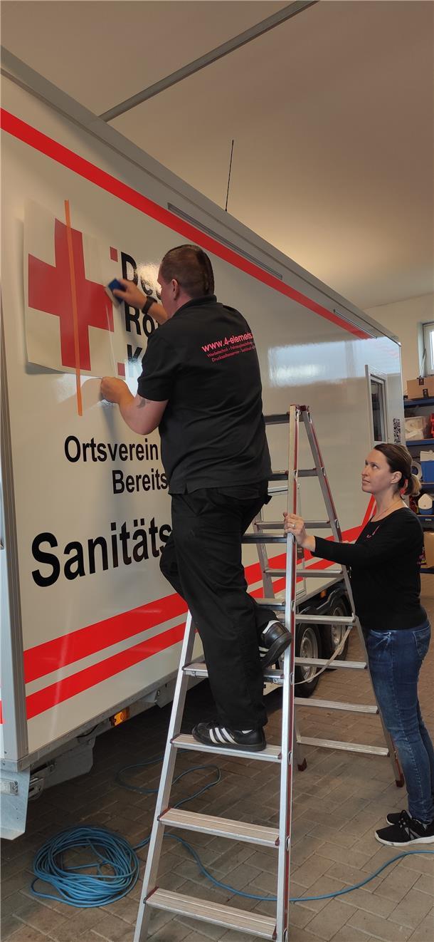 Nina und Bastian Pommert von der Firma 4-Elements bekleben die neue Sanitätswach...