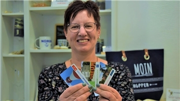 NMT-Mitarbeiterin Svenja Faehse hält drei der bisherigen Nordenham-Gutscheine in die Kamera. Ab März soll es die Einkaufsgutscheine auch in digitaler Form geben.