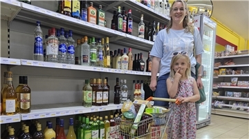 eine Frau und ein Mädchen mit einem Kinder-Einkaufswagen vor einem Supermarktregal