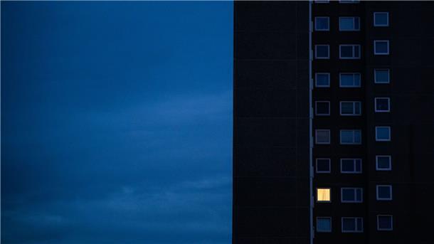 Nur einer Wohnung eines Mehrfamilienhauses brennt am frühen Morgen Licht. Die teils massiv gestiegenen Preise für Gas und Strom bereiten viele Menschen in Deutschland finanzielle Schwierigkeiten.
