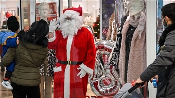 NZ-Redakteurin Ursel Kikker winkt aus dem Schaufenster bei Mode Steffen im Columbus-Center als Weihnachtsmann den Passanten zu.