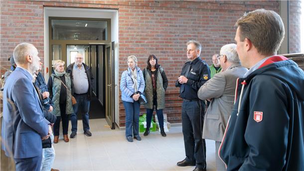 Sechs Männer und fünf Frauen stehen vor einem Polizeirevier und lächeln in die Kamera.