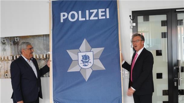 Oberbürgermeister Melf Grantz (links) und Harry Götze, der Direktor der Ortspolizeibehörde, bei der Enthüllung des neuen Logos. Der Polizei-Stern wirkt nun moderner.