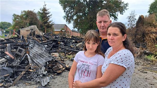 Olesya (rechts) und Heinz-Georg Mehrtens sowie Tochter Anna stehen vor den Trümmern der abgebrannten Scheune neben ihrem Wohnhaus in Driftsethe.