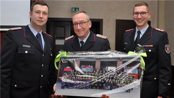 Ortsbrandmeister Hendrik Holst (links) und sein Stellvertreter Felix Haase (rechts) machen einem Mann, der die jüngere Geschichte der Bremervörder Feuerwehr wesentlich mitgeprägt hat, eine großformatige Foto-Freude: Holger Naubert, der sich zu Beginn des vergangenen Jahres aus der Führungsriege der Wehr verabschiedet hatte.