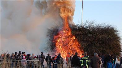 Warum so viele Dörfer im Cuxland ihr Osterfeuer vor anderen verheimlichen Menschen stehen um ein brennendes Osterfeuer herum.