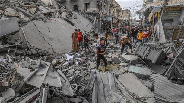 Deutsche von Hamas entführt - Evakuierungsflüge Palästinenser laufen nach einem israelischen Luftangriff im Gazastreifen zwischen den Trümmern eines zerstörten Gebäudes umher.