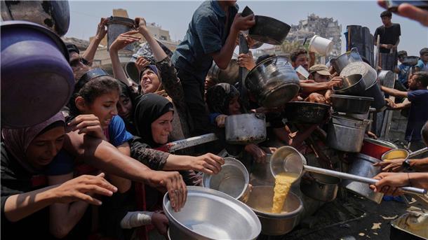Palästinenser warten an einer Ausgabestelle für gespendete Lebensmittel im Gazastreifen. (Archivbild)
