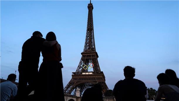 Erste Athleten beziehen Olympisches Dorf in Paris Paris-Touristen vor dem mit den olympischen Ringen geschmückten Eiffelturm.