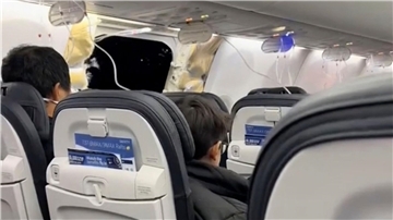 Passagiere sitzen in einer Boeing 737-9 Max in der Nähe des abgerissenen Kabinenteils.