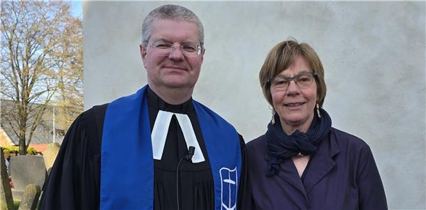 Sie ist die neue Seemannsdiakonin für die Häfen in der Wesermarsch Ein Mann, der evangelischer Pfarrer ist, und eine Seemannsdiakonin stehen vor einer Kirche.
