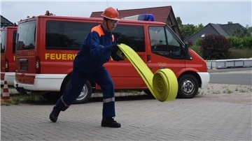 Paul Engling, Mitglied der Feuerwehr Nordenham, rollt einen Schlauch aus. 