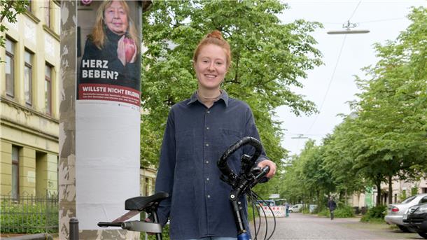Pheline Hanke radelt durch die Stadt, hält auf Litfaßsäulen und an Haltestellen Ausschau nach den riesigen Plakaten, die sie für die Frauen-Herz-Kampagne gestaltet hat.