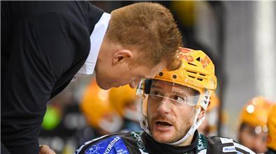 Ein Mann beugt sich herunter zu einem anderen Mann, um mit ihm zu sprechen. Es ist Trainer Alexander Sulzer von den Fischtown Pinguins mit Jan Urbas.  