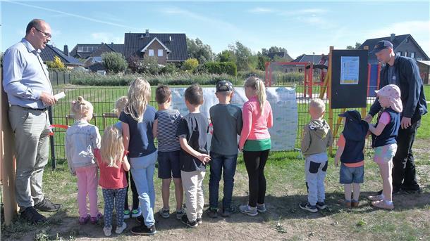 Planer Bernward Benedikt Jansen (links) und Gerke Rademacher vom Projekt „Zukunft ahoi - jetzt mal Future bei die Fische" (rechts) schauten dabei zu, wie die Kinder das Band zum neuen Spielplatz zerschnitten. Foto Ulich