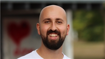 Faruk Maulawy ist von hinten zu sehen. Er wirft einen Ball in einen Basketballkorb.