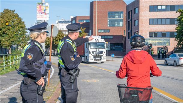 Zwei Polizisten weisen eine Radfahrerin auf ihren Fehler hin. 