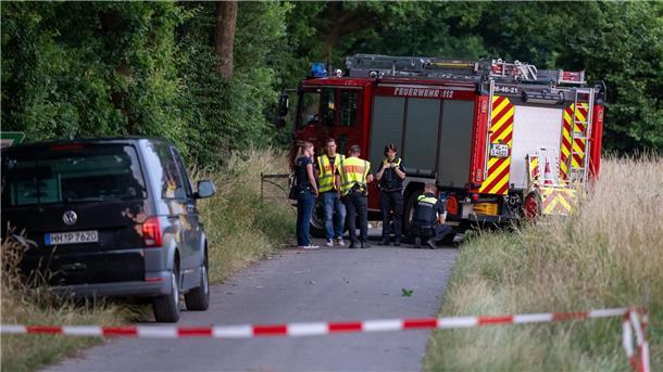 Polizisten arbeiten an der Unfallstelle, die sich hinter dem Feuerwehrfahrzeug befindet.