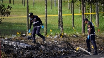 Polizisten ermittelt an der Absturzstelle des Kleinflugzeugs in Malaysia.