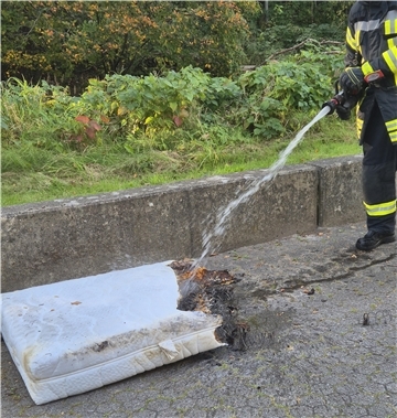 Ein Feuerwehrmann löscht eine Matratze. Polizisten löschten eine brennende Matratze im Gewerbegebiet Spaden, bevor die Feuerwehr eintraf. Diese beseitigte letzte Glutnester und verhinderte weiteren Schaden.