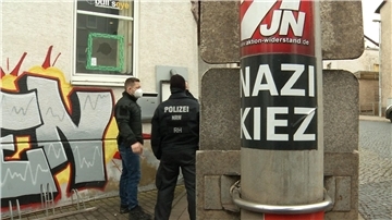 Polizisten stehen vor der Gaststätte „Bull’s Eye“. An einem Pfahl ist ein Aufkleber mit der Aufschrift „Nazi Kiez“ zu sehen.