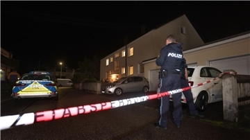 Polizisten stehen vor einem Haus, in dem drei Menschen erschossen wurden.