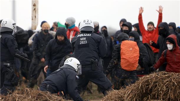 Polizisten und Demonstranten stehen sich am Rande des Braunkohletagebaus bei Lützerath gegenüber.