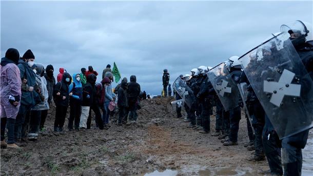 Polizisten und Demonstranten stehen sich am Rande des Braunkohletagebaus gegenüber.