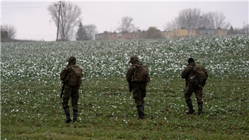 Polnische Soldaten suchen auf einem Acker nach Wrackteilen.