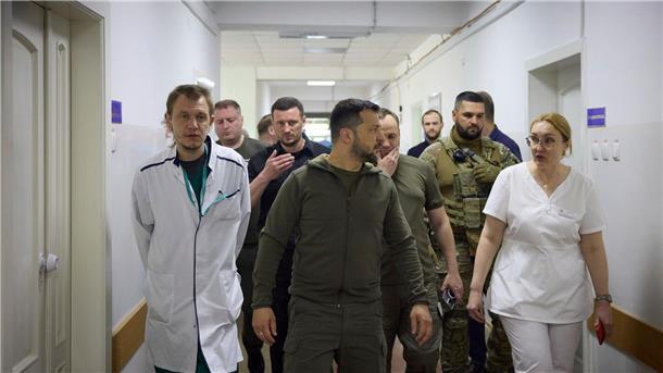 Krieg gegen die Ukraine: So ist die Lage Präsident Selenskyj (M) besucht ein Krankenhaus in dem von den Überschwemmungen betroffenen Gebiet von Cherson.