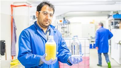 Projektleiter Faraz Rasheed Mir vom ttz zeigt eine Flasche mit Waschwasser von einer Fassadenreinigung und wie der Inhalt nach Vorreinigung und Membranfiltration aussehen soll.