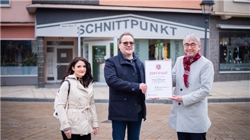 Drei Leute vor einem Friseursalon