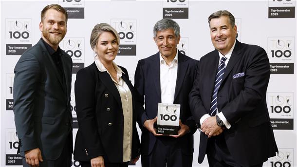 Vier Personen stehen vor einer Fotowand mit dem Logo „TOP 100 – Top-Innovator 2025“, eine Person hält die Auszeichnung in den Händen.