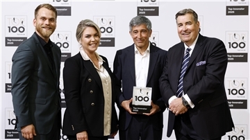 Vier Personen stehen vor einer Fotowand mit dem Logo „TOP 100 – Top-Innovator 2025“, eine Person hält die Auszeichnung in den Händen.
