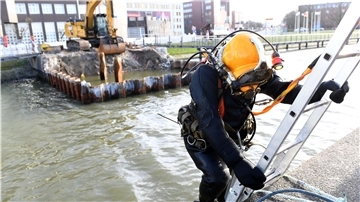 Reinhold Strazalek vom Tauchbetrieb Helgoland steigt für den Arbeitseinsatz auf einer Leiter ins wenige Grad warme Wasser des Alten Hafens.