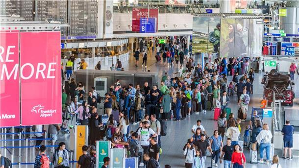 Reisende stehen am Flughafen Frankfurt Main  beim Einchecken in einer langen Schlange.