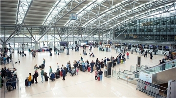 Reisende stehen im Terminal des Flughafen Hamburg mit ihrem Gepäck in einer Warteschlange an einem Check in-Schalter.
