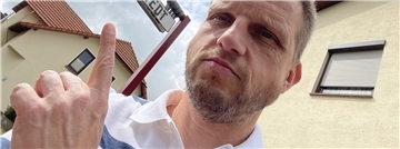 Reporter Bert Albers sitzt auf einer Mitfahrbank in Tarmstedt. Das Schild über ihm zeigt an, dass er ins Nachbardorf Wilstedt mitgenommen werden möchte.