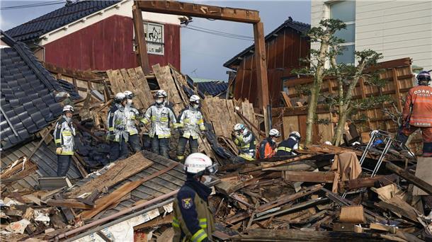 Mehr als 200 Menschen in Japans Erdbebengebiet vermisst Rettungskräfte arbeiten an einem eingestürzten Gebäude in Wajima.