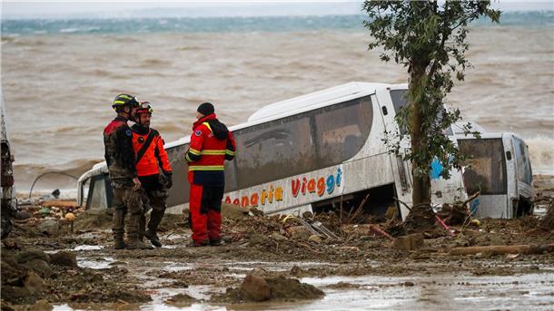 Frau stirbt bei heftigem Unwetter auf Insel Ischia Rettungskräfte auf Ischia neben einem Bus, der durch schwere Regenfälle weggeschwemmt wurde.