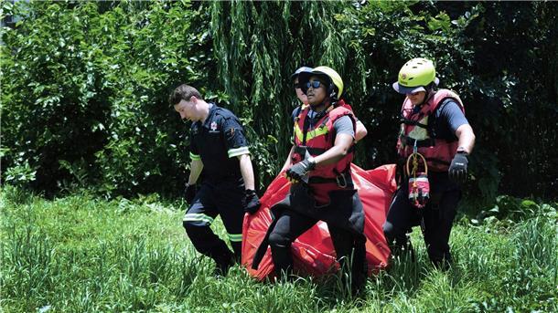 Mindestens neun Menschen ertrinken bei Taufe in Fluss Rettungskräfte tragen die Leiche eines Todesopfers, das aus dem Fluss Jukskei geborgen wurde.